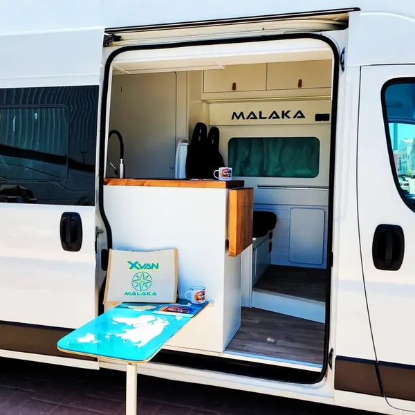Camper con la puerta lateral abierta y mesa exterior