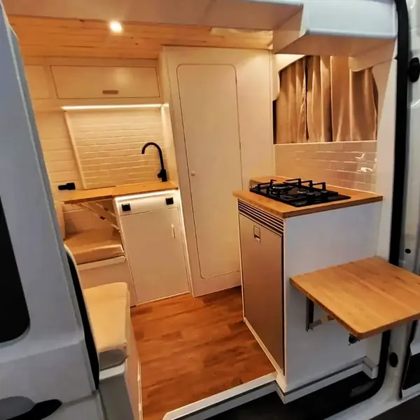Cocina de camper con fogón de gas, fregadero y mesa abatible