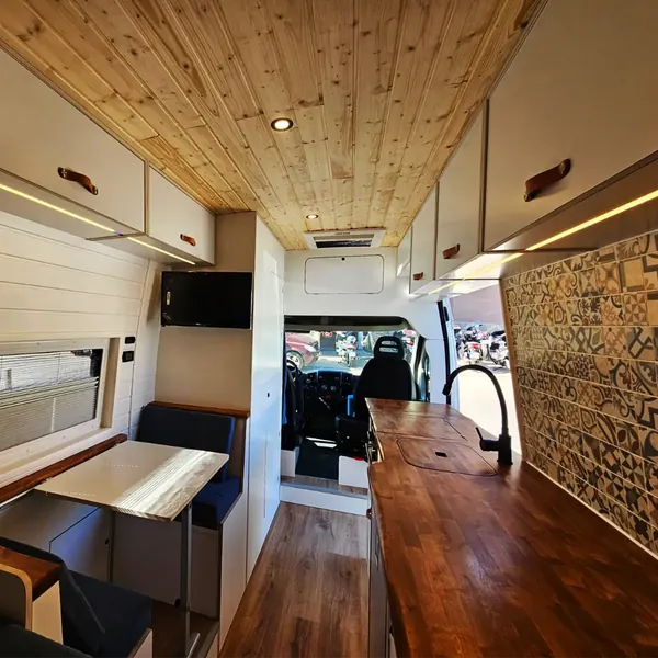 Interior de camper con encimera de madera oscura y azulejo decorativo