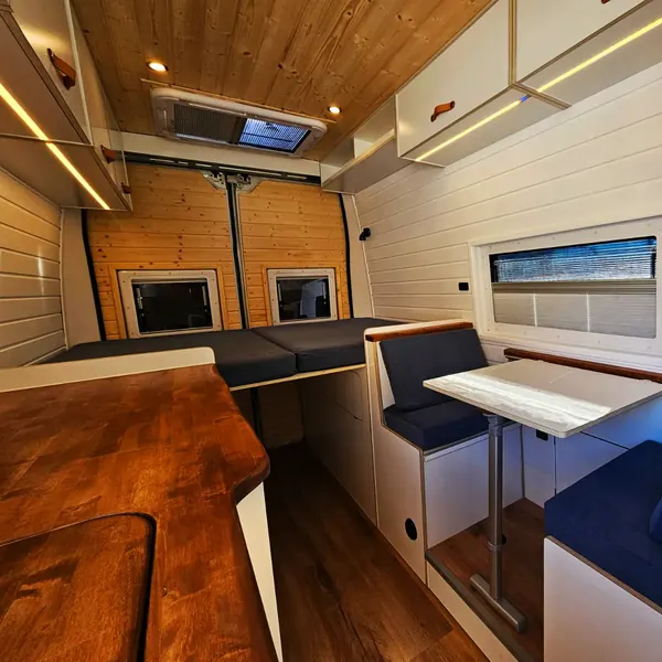 Salón de camper con asientos azules y mesa